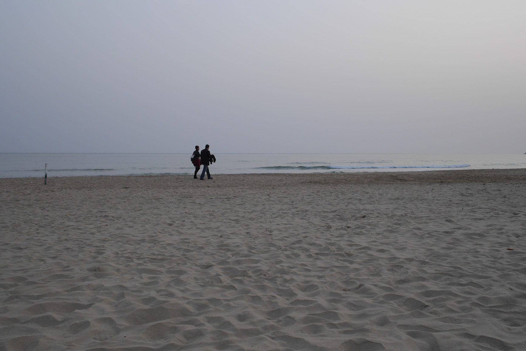 Nearly empty beach with a couple (archive)